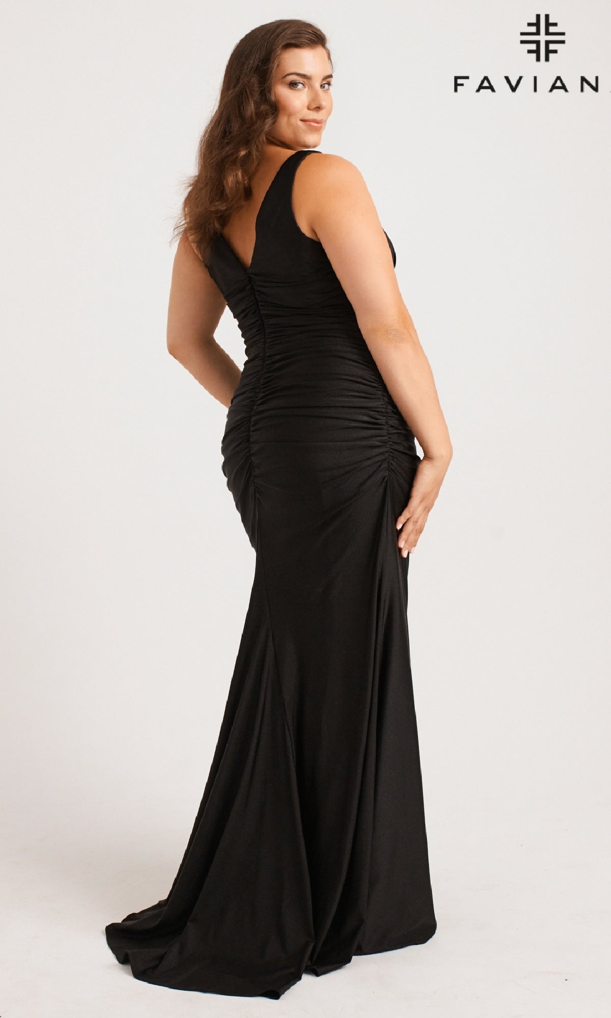 A woman models the Long Plus-Size Prom Dress: Faviana 9584, a fitted sleeveless black v-neck gown, with her back slightly turned against a plain background. The Faviana logo is in the top right corner.